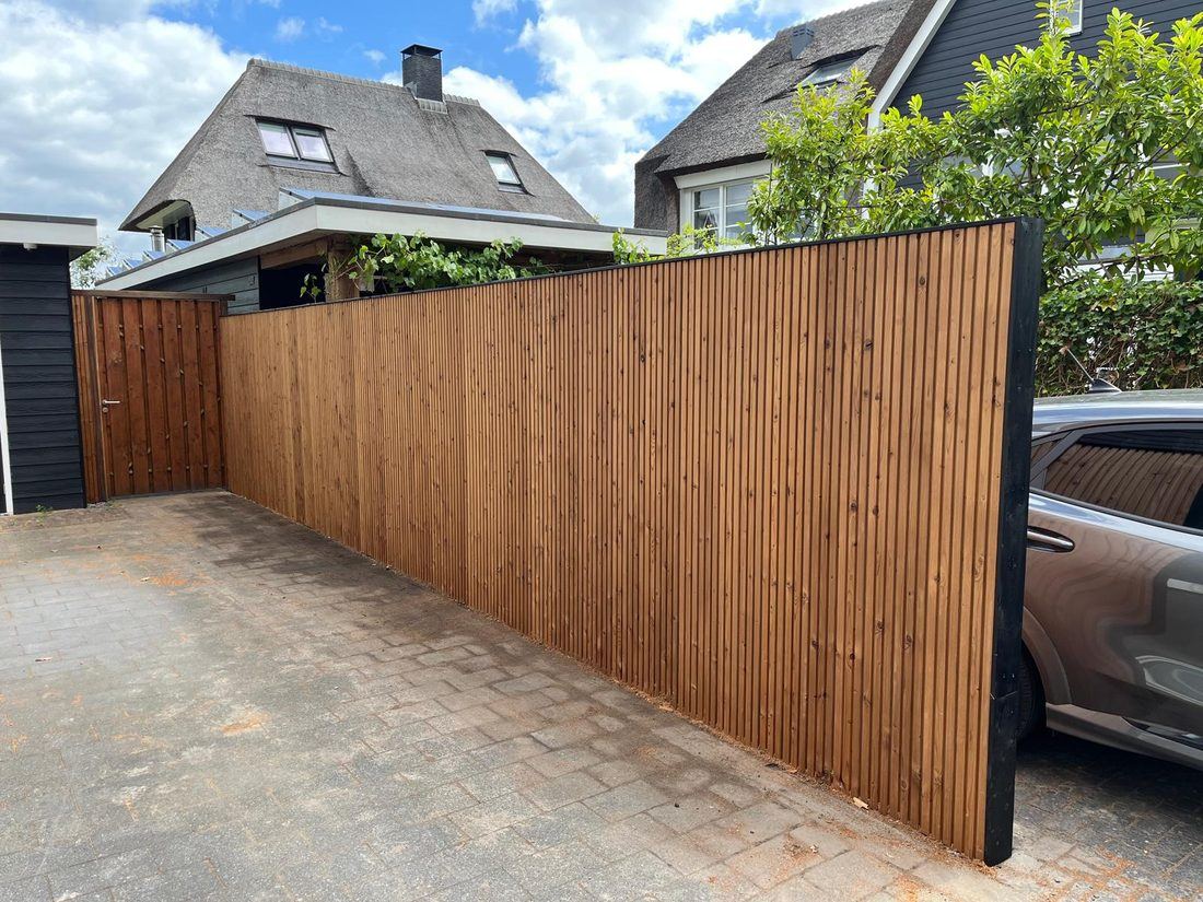 Nieuw geplaatste houten schutting langs een oprit