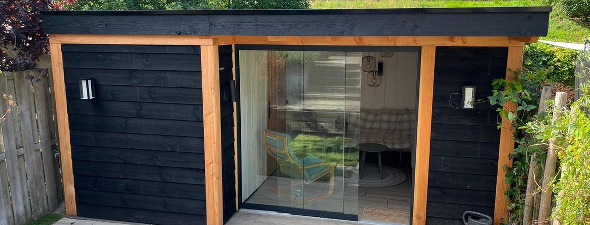 Moderne zwarte tuinkamer met houten kozijnen, schuifpui en groendak