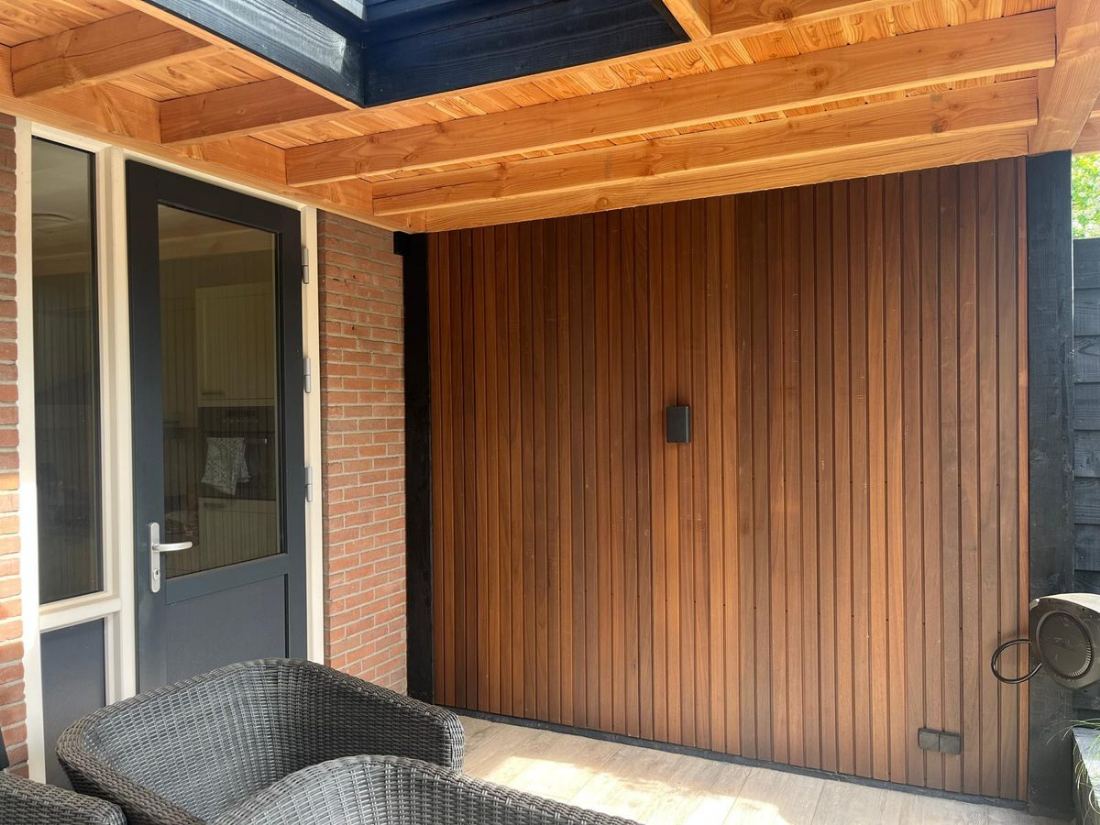 Tuinhuis met warme houten gevel en overkapping bij de entree